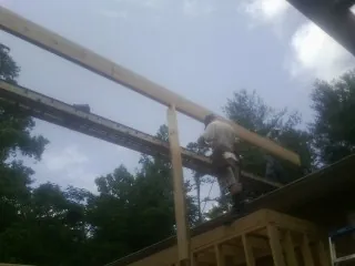 Carpenter setting a ridge beam over a new addition frame — Ice Dam Removal by Roofing Brothers in Rensselaer