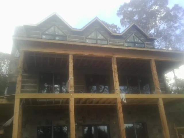 Dormers and porch framing on a large log home under construction — Roof Coating work by our crew in Rensselaer