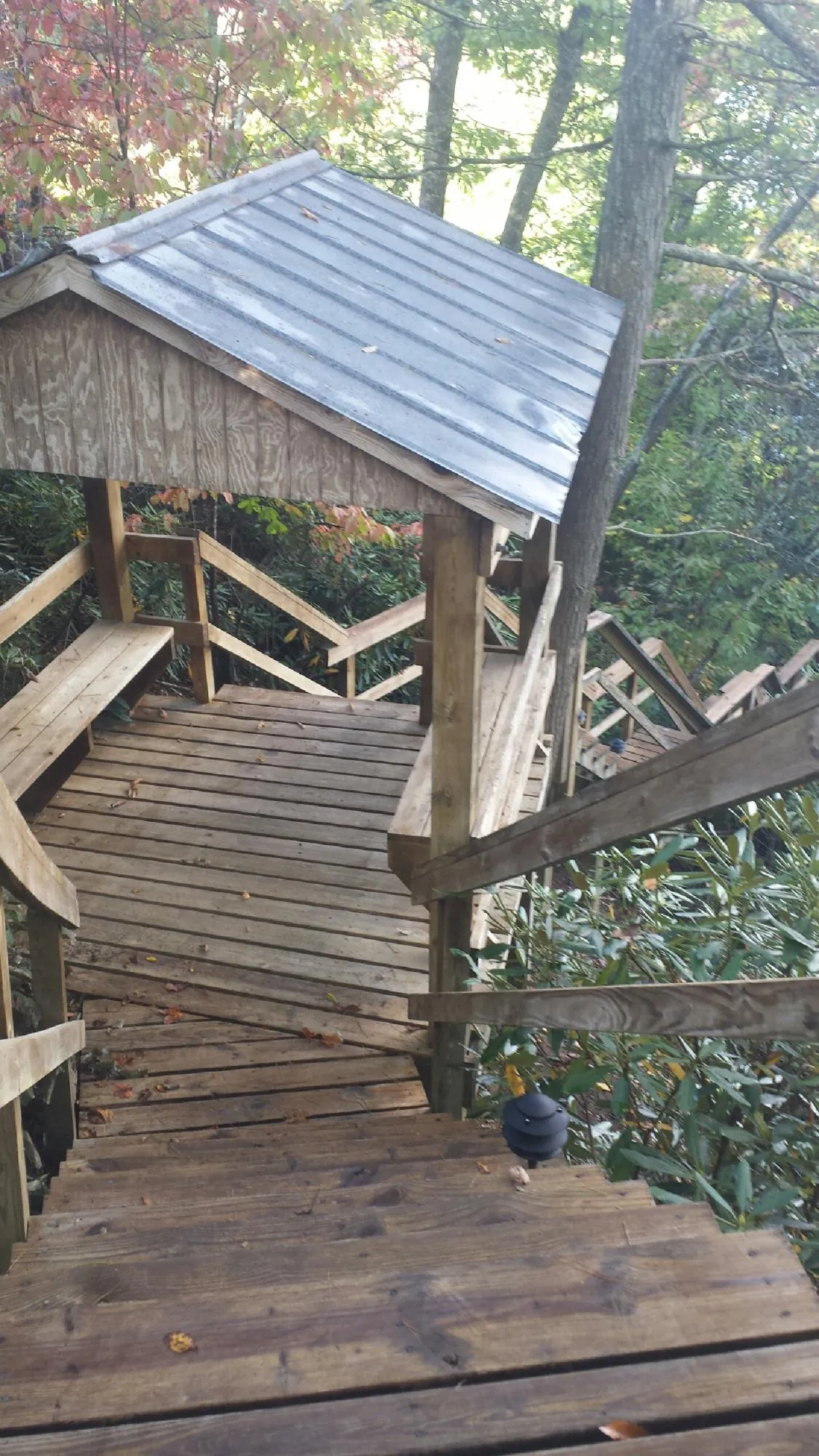 Metal roofed shelter over wooden steps on a wooded walkway — Skylight Repair & Installation work by our crew in Rensselaer